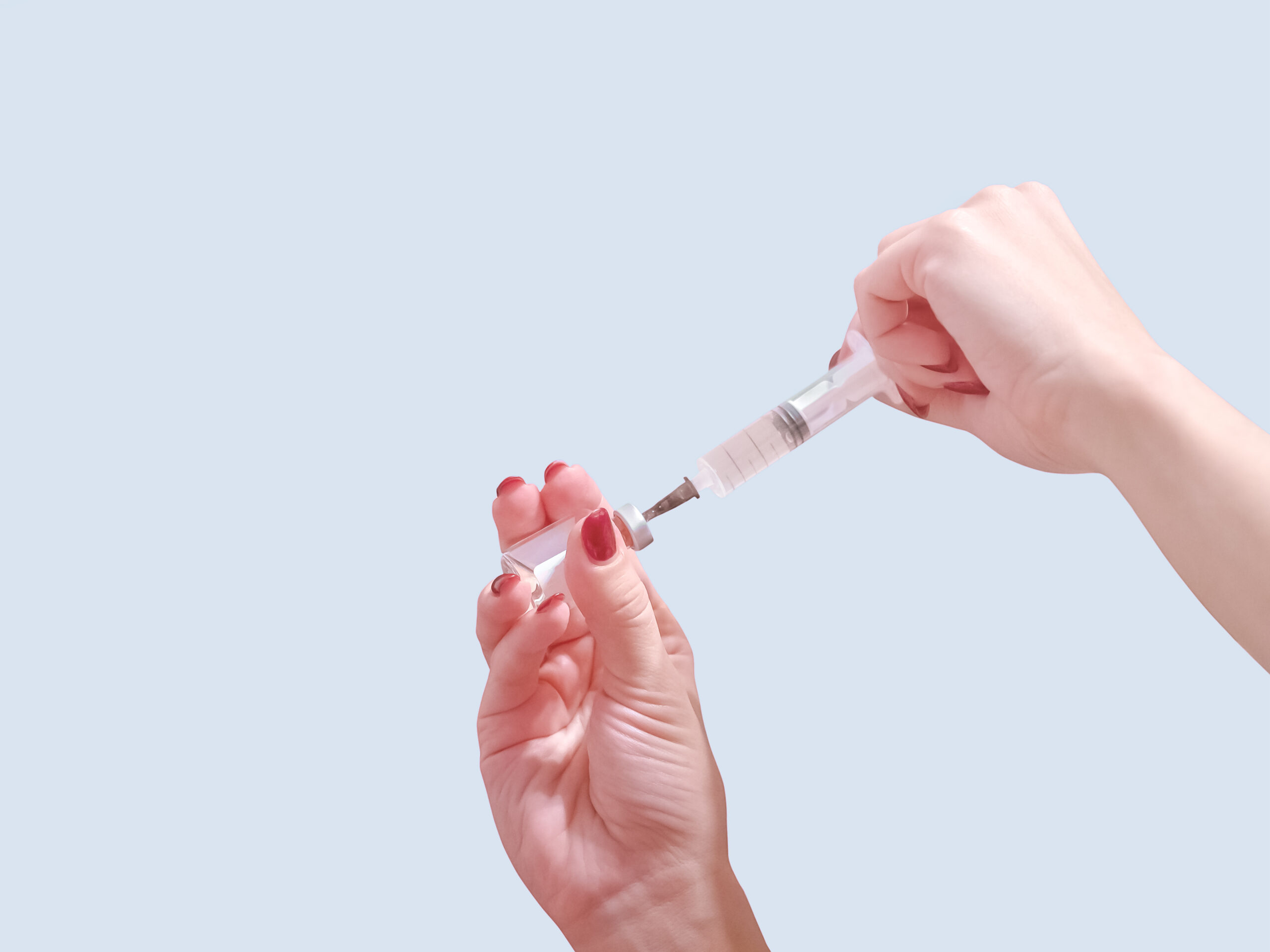 A hand with red nails holds a syringe. Girl holds a syringe for pointed. Medicine. Cold blue background, place for text.